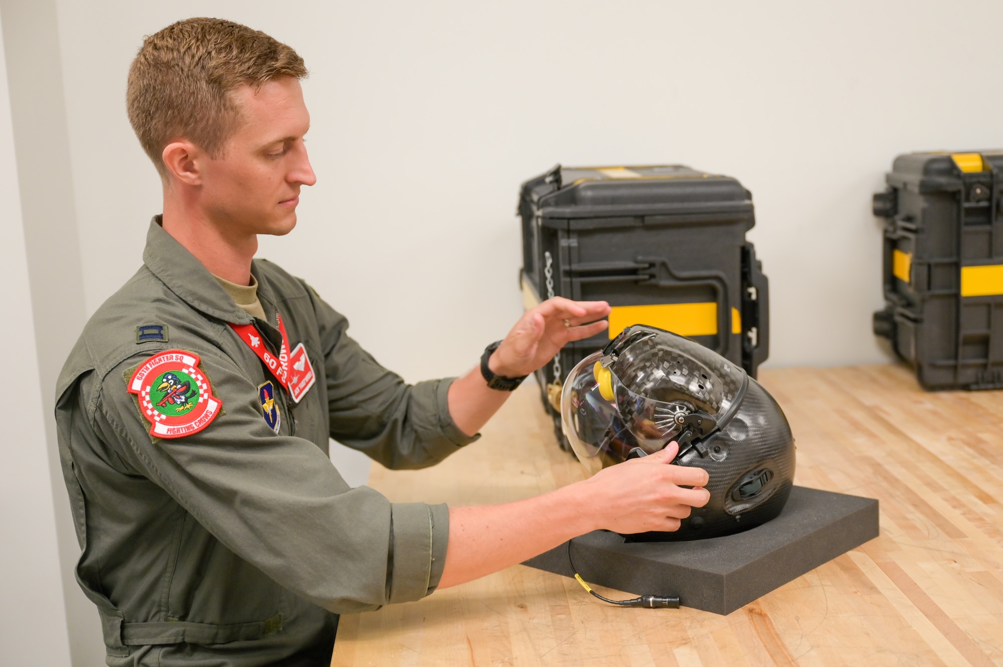 A photo of an airman looking at a helmet.