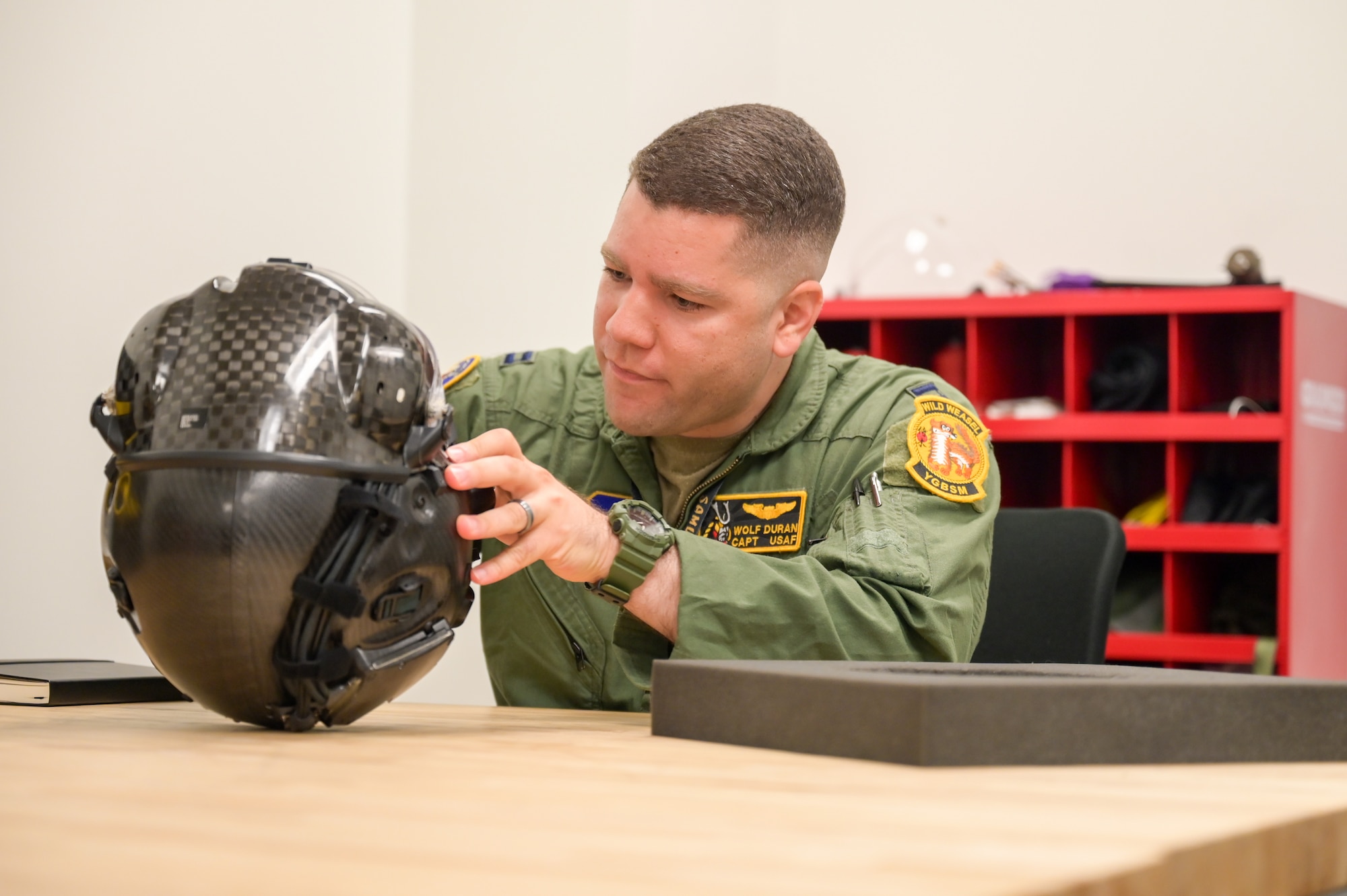 A photo of an airman looking at helmet.