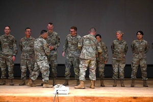 Airmen are recognized with coins on a stage.