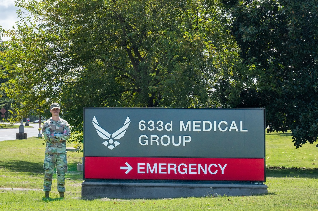 A uniformed man stands by a hospital sign.