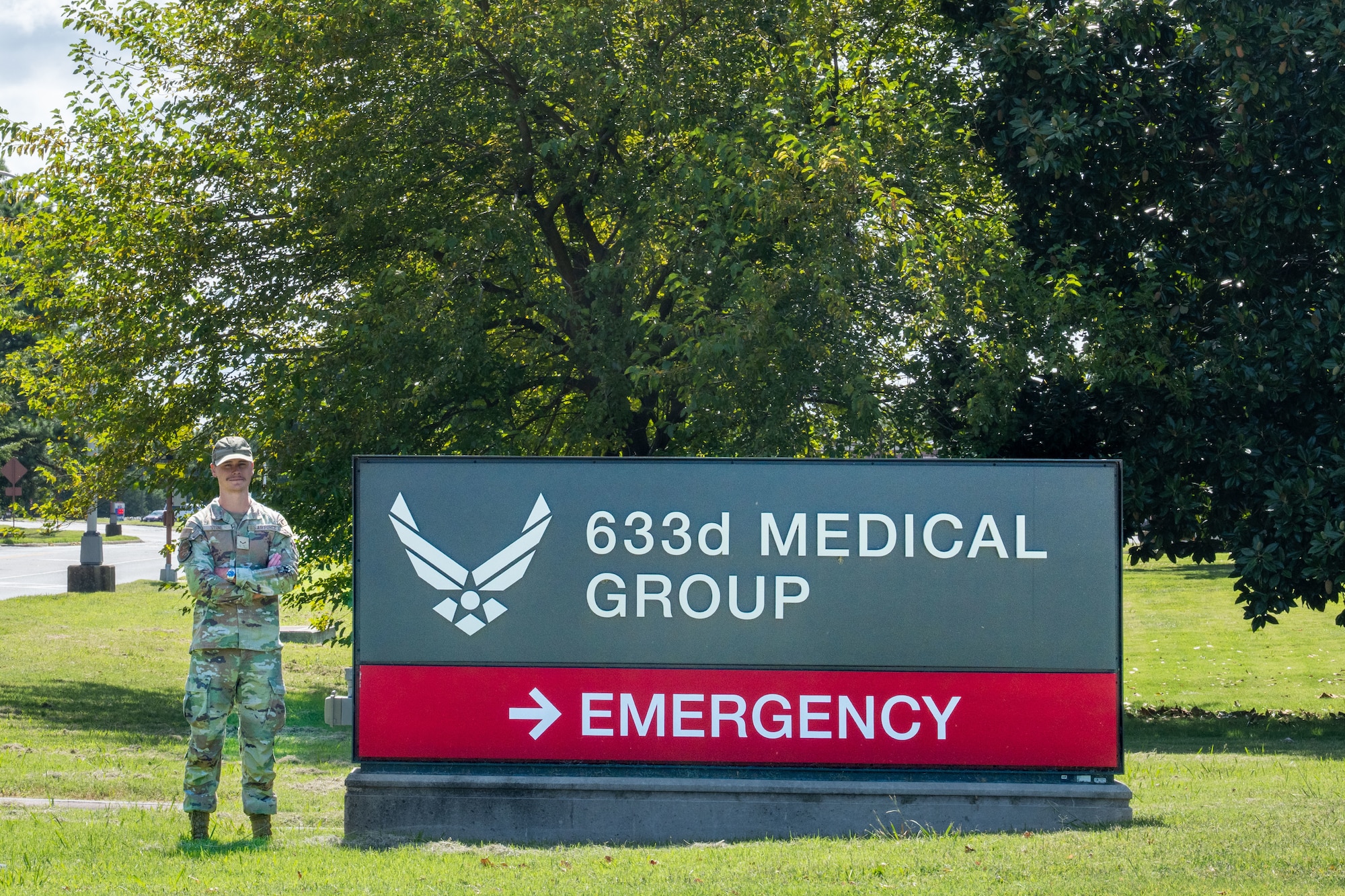 A uniformed man stands by a hospital sign.