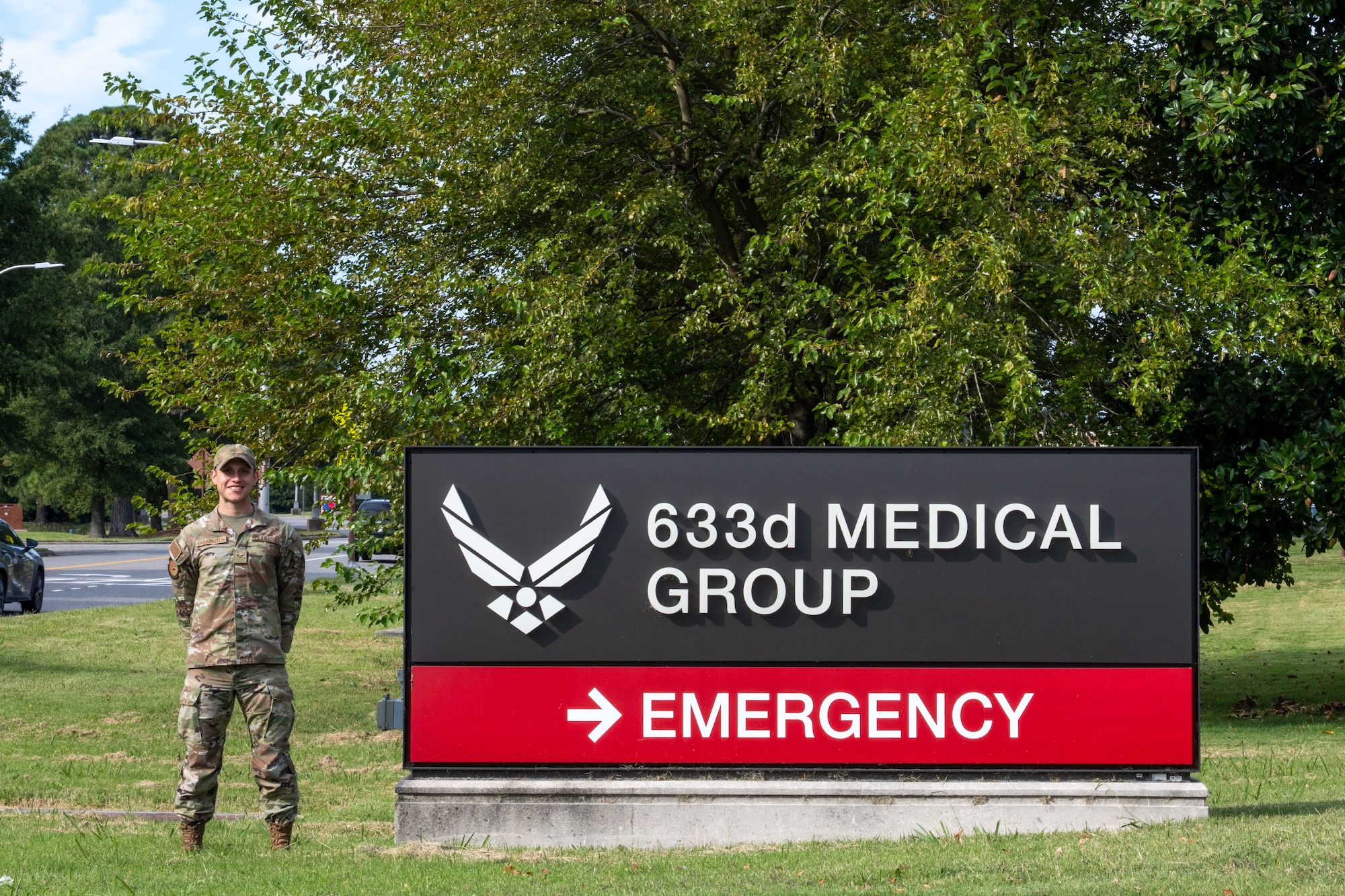 A uniformed man stands by a hospital sign.