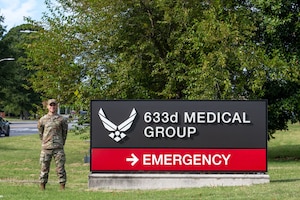 A uniformed man stands by a hospital sign.