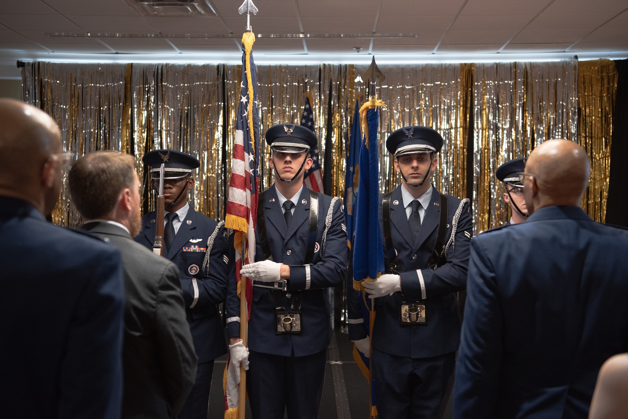 Airmen holding american flag flanked by rifles