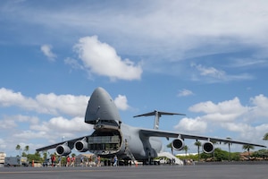 Students from across Oahu walk towards a C-5 Galaxy on the flightline of Joint Base Pearl Harbor-Hickam, Hawaii, during the Wings of Aloha Student Expo.