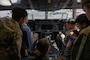 U.S. Air Force Junior Reserve Officer Training Corps cadets sit in the cockpit of a C-17 Globemaster III with a pilot.