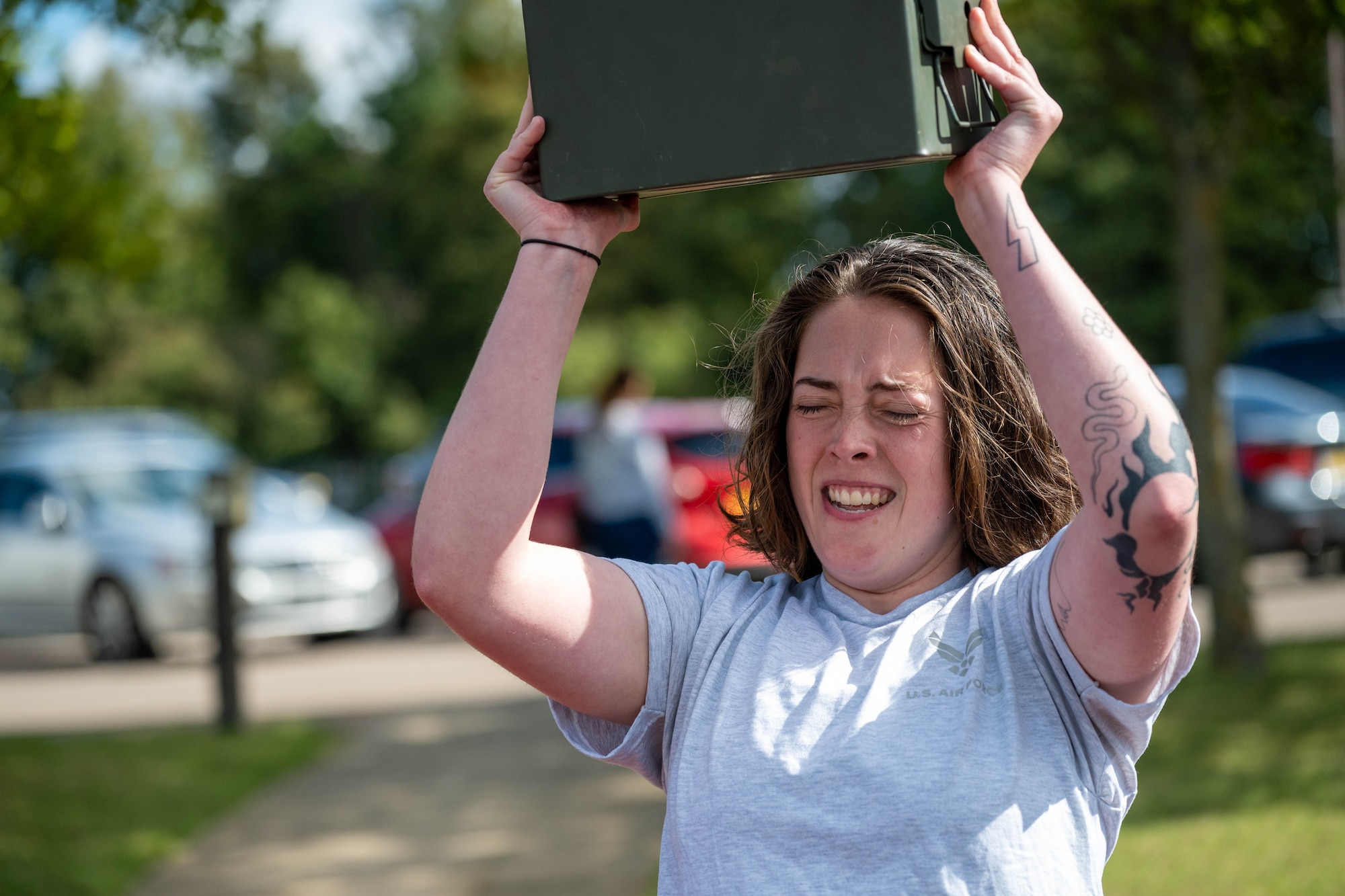 An Airman lifts an ammunition can overhead during a combat fitness challenge