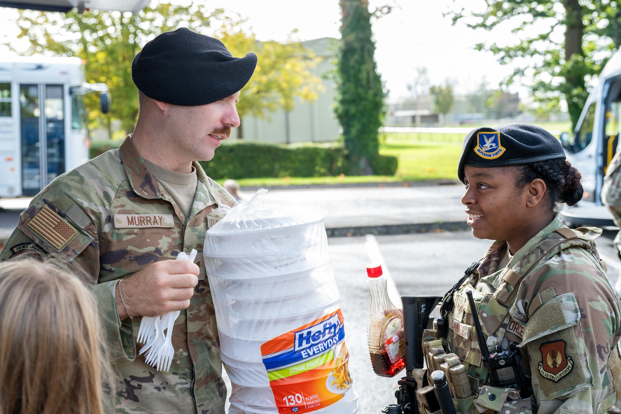 Defenders carry a stack of pancakes and supplies during a USO breakfast