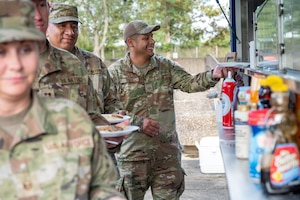 An Airman smiles while receiving pancakes during a USO breakfast