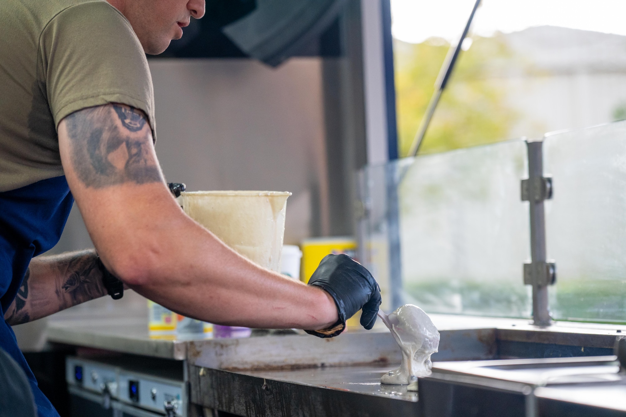 A USO volunteer pours pancake batter onto a griddle