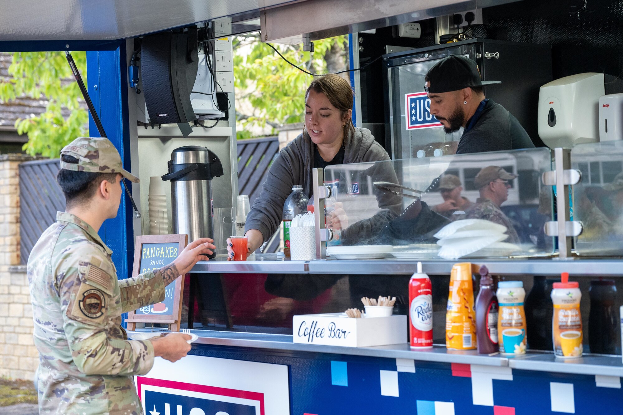 A USO volunteer serves a drink to an Airman