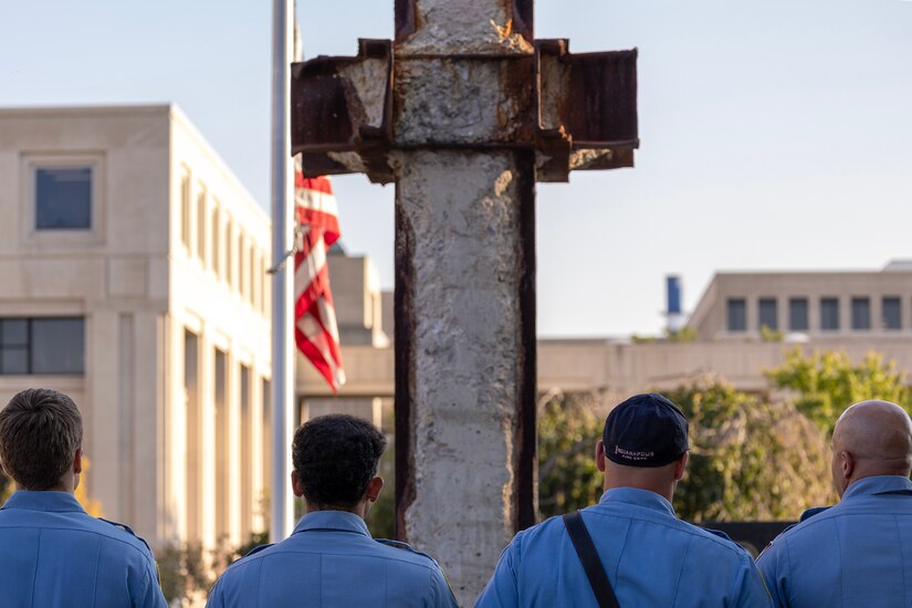 Firefighters from the Indianapolis Fire Department’s Station 13 pay honors to the American Flag during the National Anthem during a commemoration ceremony at the Indiana 9/11 Memorial in Indianapolis Sept. 11, 2025. Standing between the firefighters and the flag was a beam from one of the towers at the World Trade Center, which was destroyed by the terrorist attacks on Sept. 11, 2001. (U.S. Army photo by Mark R. W. Orders-Woempner)