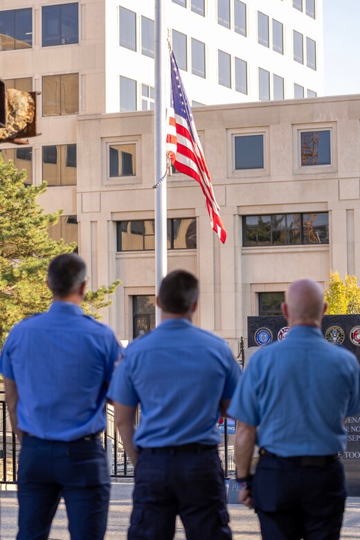 Firefighters from the Indianapolis Fire Department’s Station 13 pay honors to the American Flag during the National Anthem during a commemoration ceremony at the Indiana 9/11 Memorial in Indianapolis Sept. 11, 2025. Standing between the firefighters and the flag was a beam from one of the towers at the World Trade Center, which was destroyed by the terrorist attacks on Sept. 11, 2001. (U.S. Army photo by Mark R. W. Orders-Woempner)