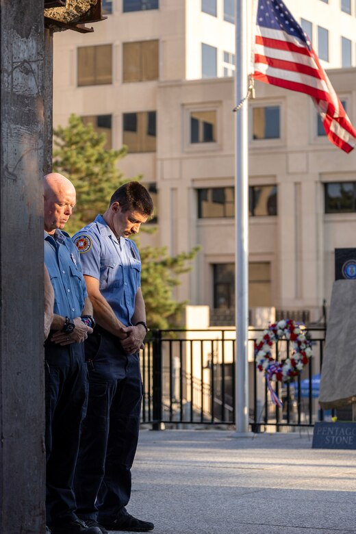 Firefighters from the Indianapolis Fire Department’s Station 13 take part in a moment of silence during a commemoration ceremony at the Indiana 9/11 Memorial in Indianapolis Sept. 11, 2025. Standing between the firefighters and the flag was a beam from one of the towers at the World Trade Center, which was destroyed by the terrorist attacks on Sept. 11, 2001. (U.S. Army photo by Mark R. W. Orders-Woempner)