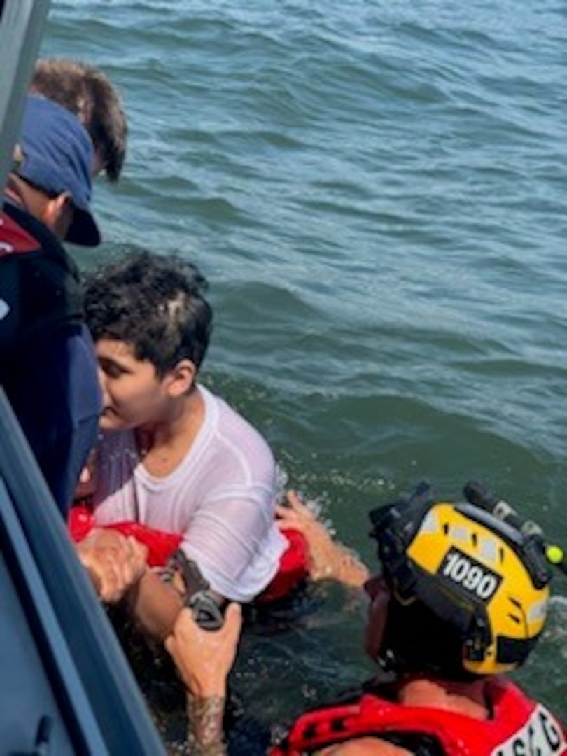 One of the three mariners is assisted by the rescue swimmer and Station Freeport members onto the Coast Guard small boat.