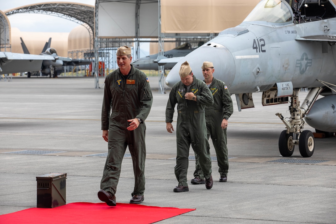 From left to right, U.S. Navy Capt. Brian Kesselring, the commanding officer of Carrier Air Wing (CVW) 5, Cmdr. Justin Reddick, the outgoing commander officer of Strike Fighter Squadron (VFA) 195, CVW-5, and Cmdr. Joseph Burns, the oncoming commanding officer of VFA-195, CVW-5, arrive at a change of command ceremony held at Marine Corps Air Station Iwakuni, Japan, Sept. 4, 2025. VFA-195 held the change of command ceremony to formally transfer command from Cmdr. Justin Reddick to Cmdr. Joseph Burns, symbolizing the shift in leadership, authority, and responsibility of VFA-195. (U.S. Marine Corps photo by Lance Cpl. Micah Taylor)