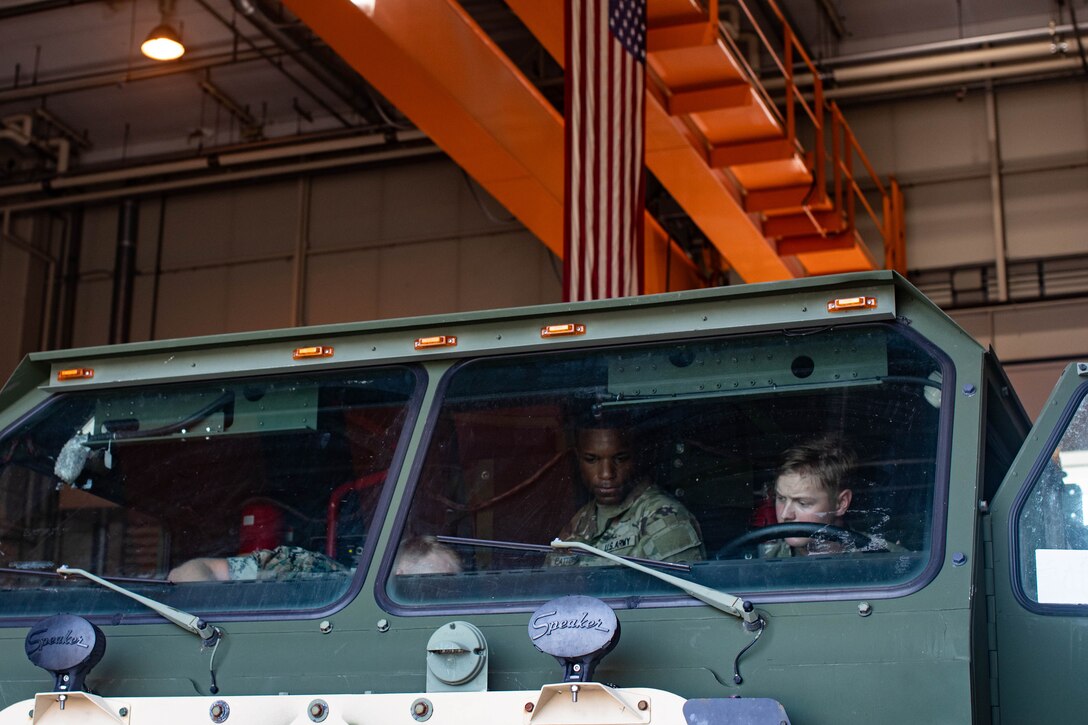 U.S. Marine with Marine Wing Support Squadron (MWSS) 171, Marine Aircraft Group (MAG) 12, 1st Marine Air Wing (MAW) teaches the functions of a LVSR MKR16 Tractor to Edward Patterson, middle, a Multiple Launch Rocket System (MLRS)/High Mobility Artillery Rocket System (HIMARS) Crewmember and Jacob day, right, a payload delivery system driver, both U.S. Army Specialist with 5-3 Long Range Firing Battalion, 3rd Multi-Domain Task Force (3MDTF), at Marine Corps Air Station Iwakuni, Japan, August 29, 2025. This training was conducted to familiarize both units with the unique equipment each force utilizes, providing mutual understanding and enhancing cohesion between the Marine and Army units for future joint operational effectiveness. 3MDTF will use the LVSR MKR16 as a prime mover for the Typhon system during Resolute Dragon 25. (U.S. Marine Corps photo by Lance Cpl. Donald Dugger)