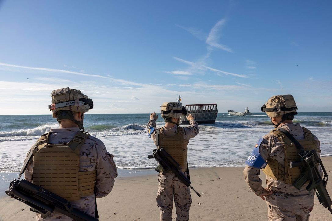 Marino Manuel Gomez Orihuela, Marino Pablo Reina Lancetaca and Cabo Primero Luis Alberto Rey Garcia, marines with Infantería de Marina (Spanish marine corps), direct incoming landing craft mechanized in preparation to execute exercise UNITAS 2025, at Onslow Beach, Marine Corps Base Camp Lejeune, North Carolina, Sep. 12, 2025. UNITAS, which is Latin for “unity,” was conceived in 1959 and has taken place annually since first conducted in 1960. This year marks the 66th iteration of the world’s longest running annual multinational maritime exercise. (U.S. Marine Corps photo by Lance Cpl. Payton Goodrich)