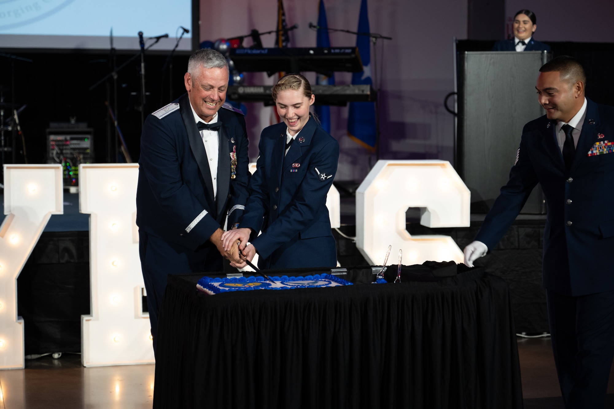 U.S. Air Force Brig. Gen. Corey Simmons, Air Mobility Command director of strategy, plans, programs and requirements, and Airman Megan Mayberry, 317th Operations Support Squadron aircrew flight equipment apprentice, cut the ceremonial cake during the Dyess Air Force Ball at the Abilene Convention Center, Abilene, Texas, Sept. 6, 2025. By tradition, the most senior and most junior Airmen in attendance cut the cake together. (U.S Air Force Photo by Airman 1st Class Caleb Schellenberg)