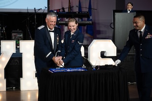 U.S. Air Force Brig. Gen. Corey Simmons, Air Mobility Command director of strategy, plans, programs and requirements, and Airman Megan Mayberry, 317th Operations Support Squadron aircrew flight equipment apprentice, cut the ceremonial cake during the Dyess Air Force Ball at the Abilene Convention Center, Abilene, Texas, Sept. 6, 2025. By tradition, the most senior and most junior Airmen in attendance cut the cake together. (U.S Air Force Photo by Airman 1st Class Caleb Schellenberg)
