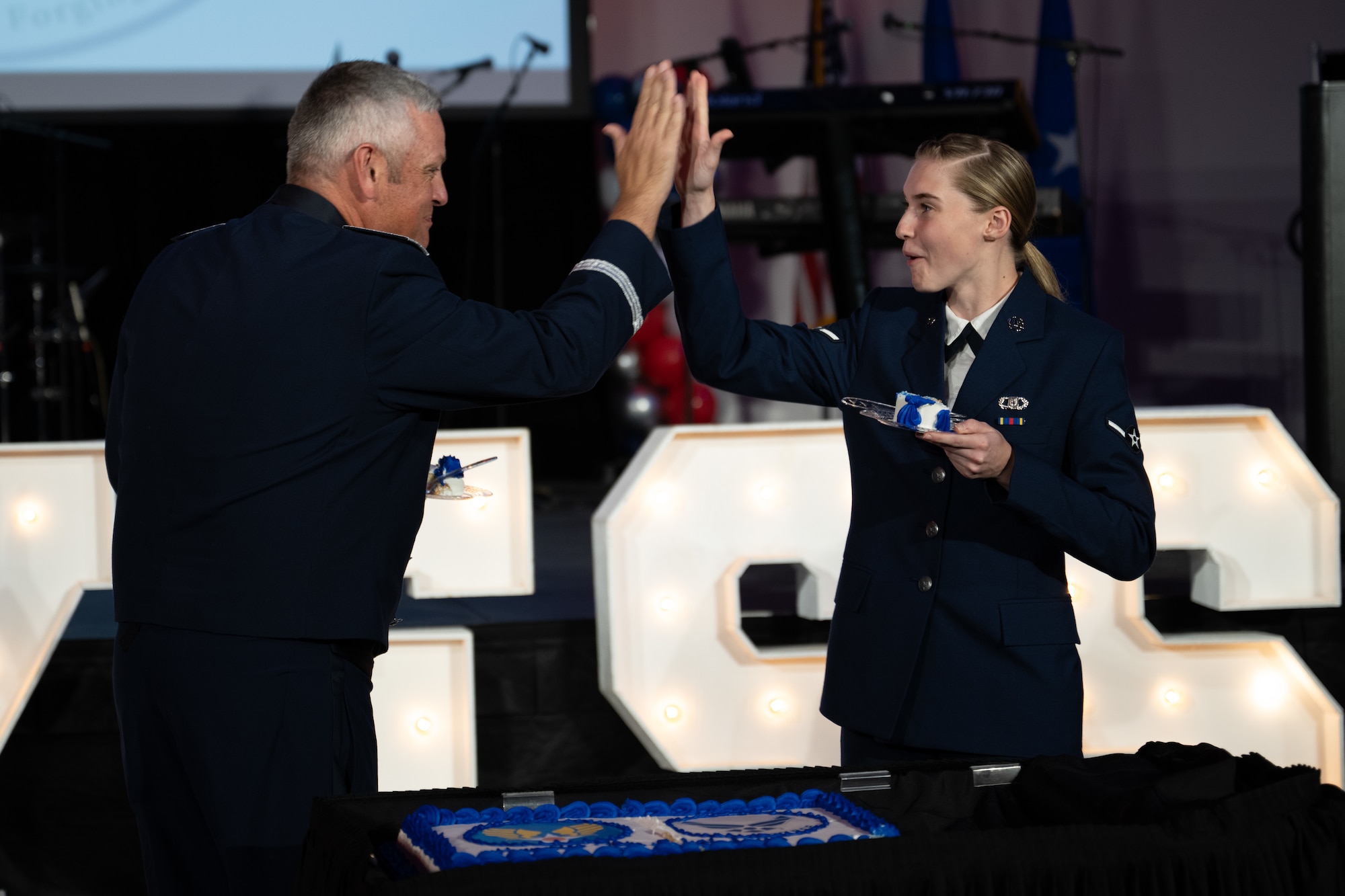 U.S. Air Force Brig. Gen. Corey Simmons, Air Mobility Command director of strategy, plans, programs and requirements, and Airman Megan Mayberry, 317th Operations Support Squadron aircrew flight equipment apprentice, celebrate after cutting the ceremonial cake during the Dyess Air Force Ball at the Abilene Convention Center, Abilene, Texas, Sept. 6, 2025. The cake cutting pairs the most senior and mot junior Airmen to symbolize Air Force heritage and the next generation. (U.S Air Force Photo by Airman 1st Class Caleb Schellenberg)