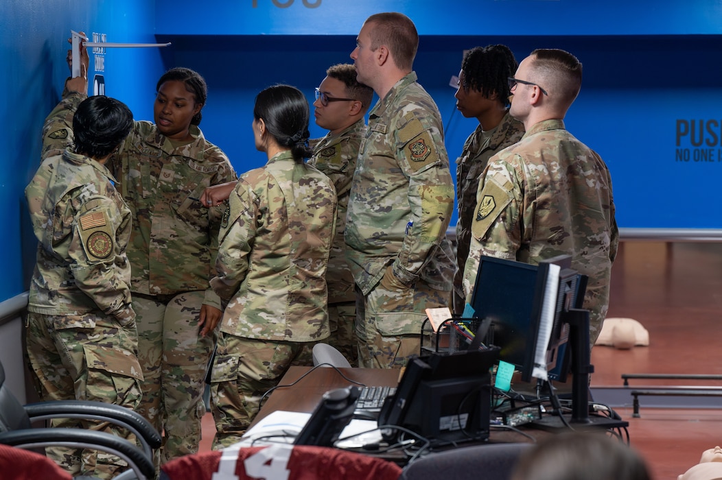U.S. Air Force Tech. Sgt. Imani Williams, 375th Force Support Squadron fitness and sports operations manager demonstrates how to record height and weight as augmentees take notes during a training at Scott AFB.