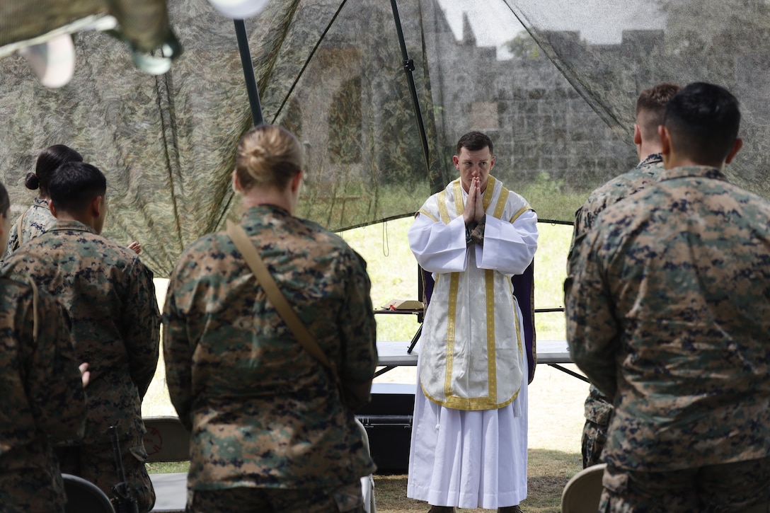 U.S. Navy Lt. Rene Pellessier, a Chaplain, administers Catholic Mass to Marine and Sailors with the III Marine Expeditionary Force outside the combat operations center in Combat Town, Camp Hansen, Okinawa Japan, Sept. 14, 2025, during the Command Post Exercise portion of Resolute Dragon 25. Resolute Dragon 25 is an annual bilateral exercise across Japan, including the southwest islands, that strengthens the command, control and multidomain maneuver capabilities of III MEF and the Japan Ground Self-Defense Force’s Western Army personnel, alongside representatives across the U.S. and Japanese Joint Force, with a focus on controlling and defending key maritime terrain. (U.S. Marine Corps photo by Gunnery Sgt. Daniel Wetzel)