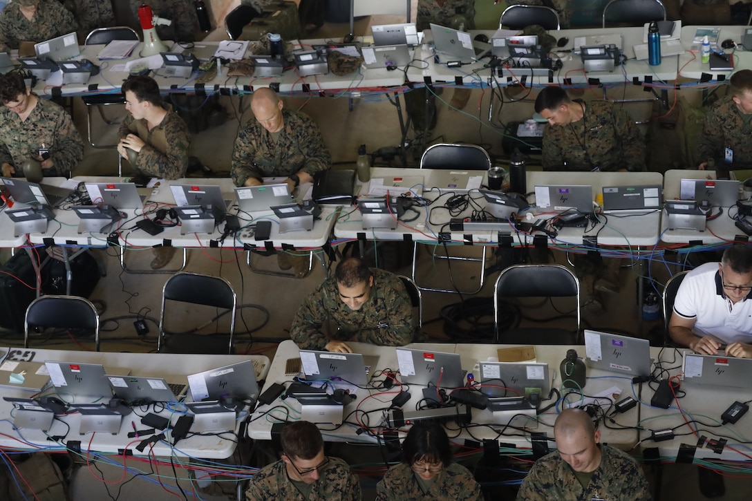 U.S. Marines and Sailors with III Marine Expeditionary Force conduct simulated battle drills while working in the III MEF combat operations center in Combat Town, Camp Hansen, Okinawa Japan, Sept. 13, 2025, during the Command Post Exercise portion of Resolute Dragon 25. Resolute Dragon 25 is an annual bilateral exercise across Japan, including the southwest islands, that strengthens the command, control and multidomain maneuver capabilities of III MEF and the Japan Ground Self-Defense Force’s Western Army personnel, alongside representatives across the U.S. and Japanese Joint Force, with a focus on controlling and defending key maritime terrain. (U.S. Marine Corps photo illustration by Gunnery Sgt. Daniel Wetzel) Photo has been edited for operational security.