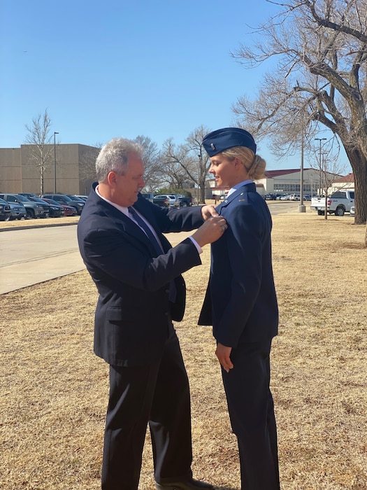 Capt. (Ret.) Robert Pickrell Jr. helps pin new pilot wings on his daughter Capt. Cassidy Pickrell at her Undergraduate Pilot Training Graduation.