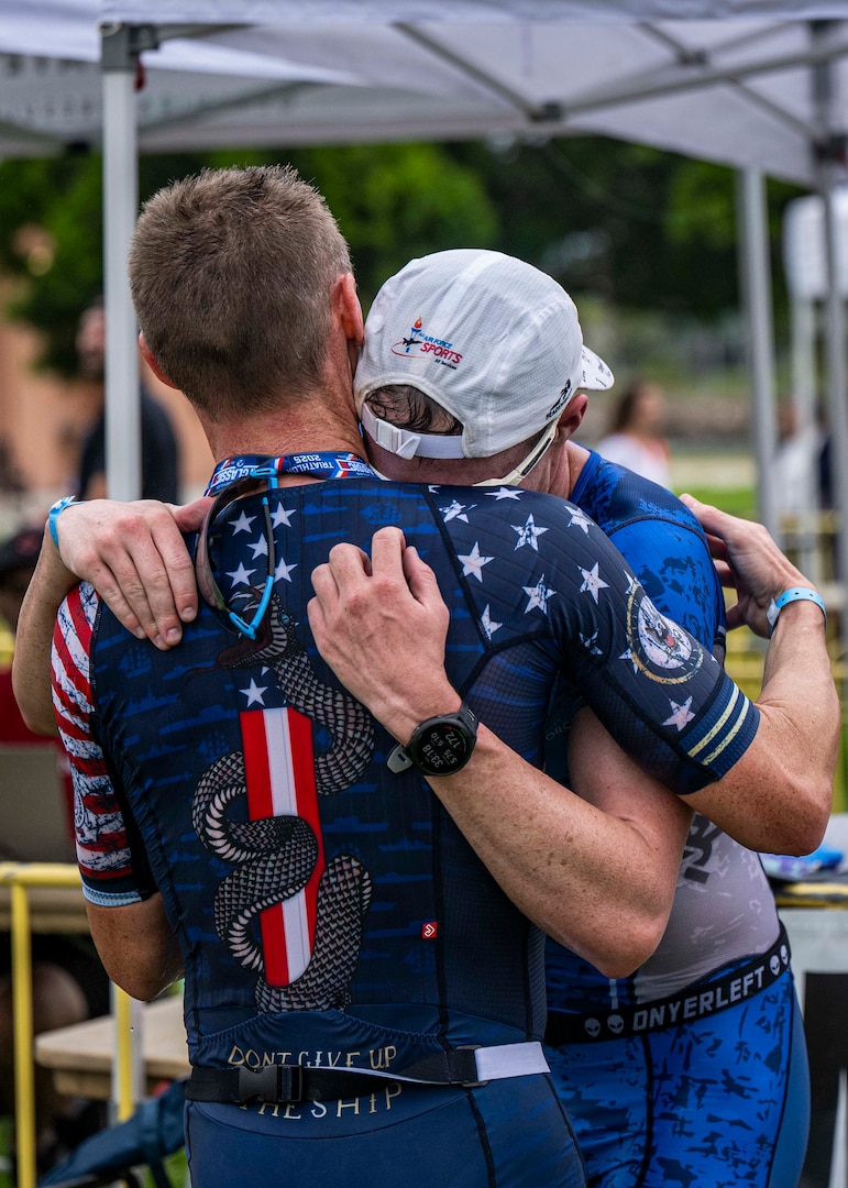 Navy Cmdr. Kyle Hooker, the winner of the 2025 Armed Forces Triathlon Championship, embraces runner-up, Air Force 2nd Lt. Mark Romano. (U.S. Armed Forces Sports phot by Mass Communications Specialist First Class Colby Mothershead - released)