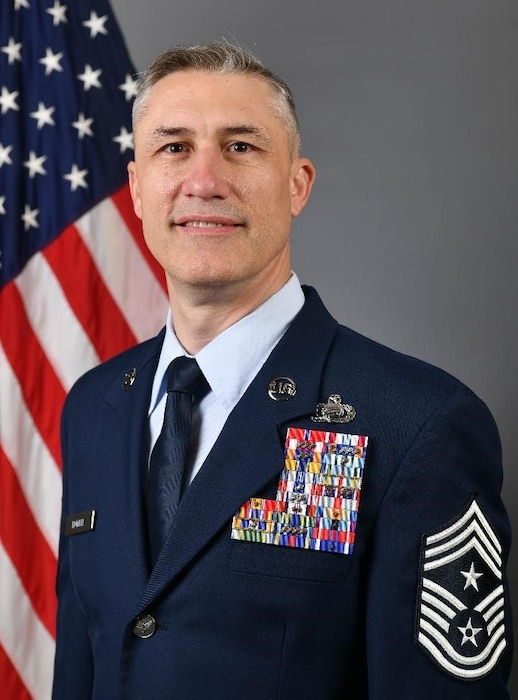 Airman in blues sitting in front of U.S. flag