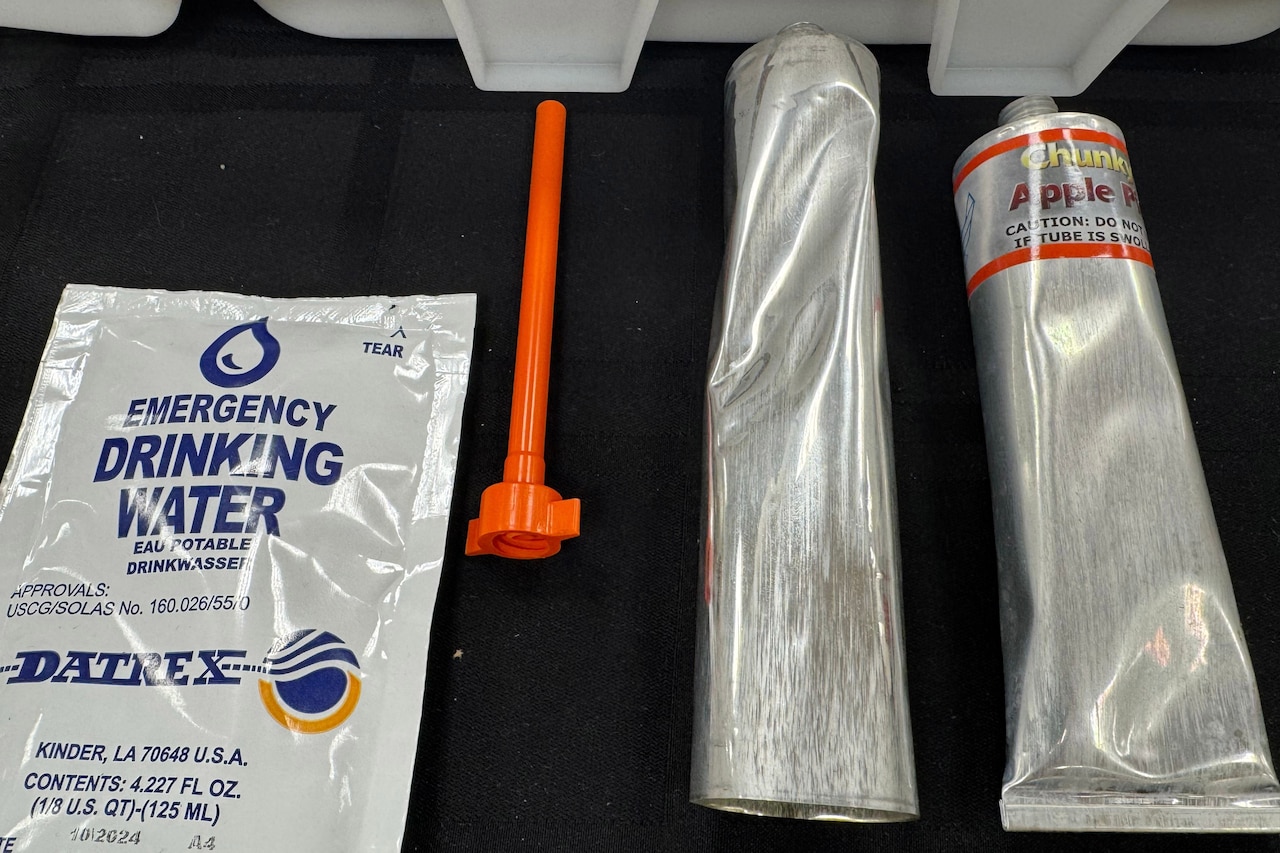 A plastic package sits beside a small funnel and two long metal tubes.