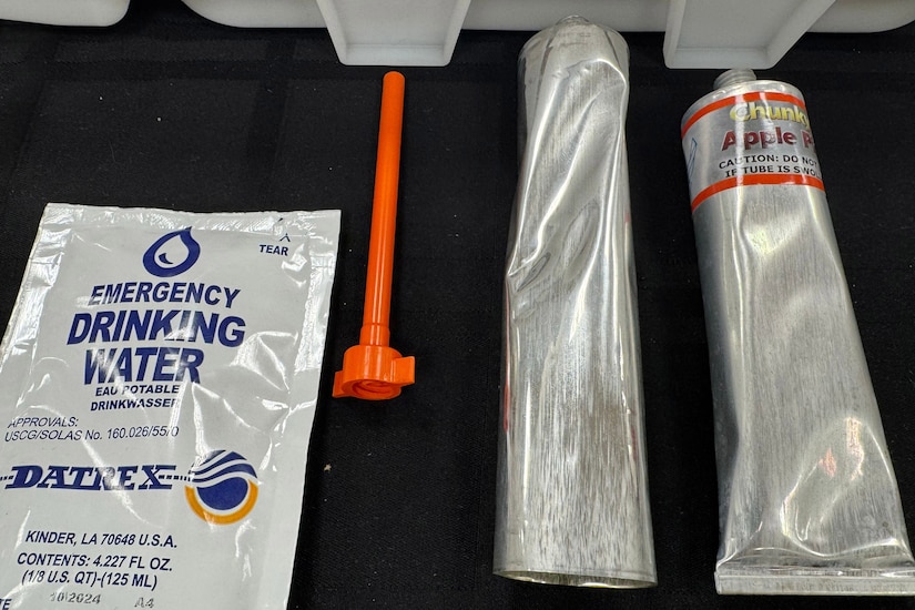 A plastic package sits beside a small funnel and two long metal tubes.