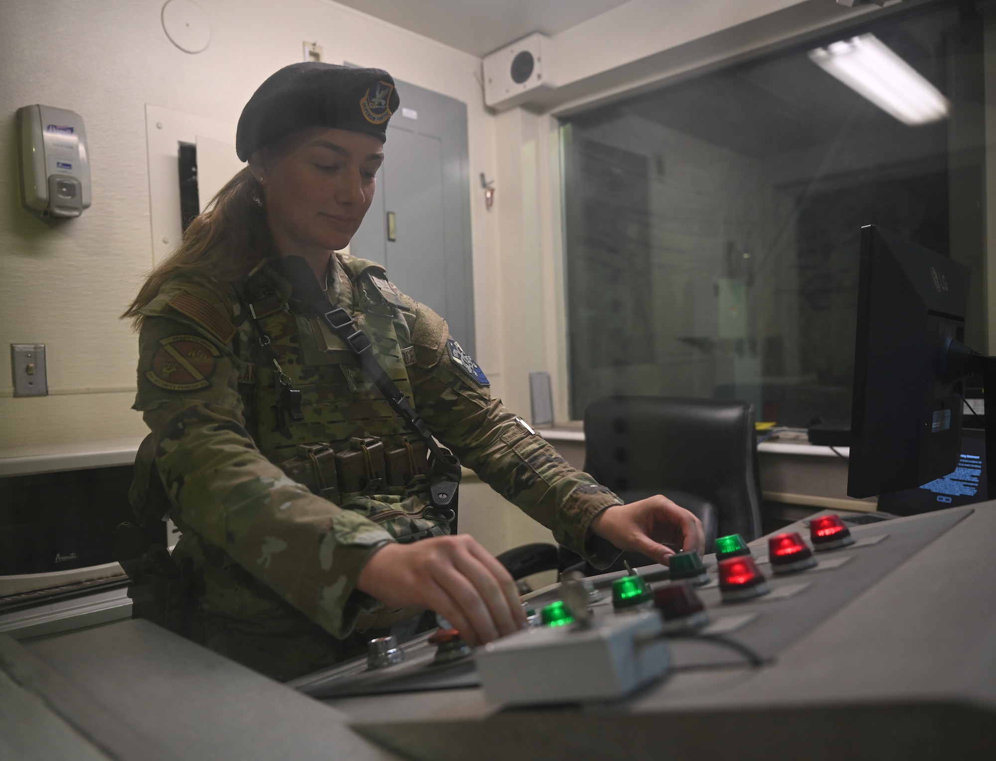 Senior Airman Brady Lander stands behind a control panel.