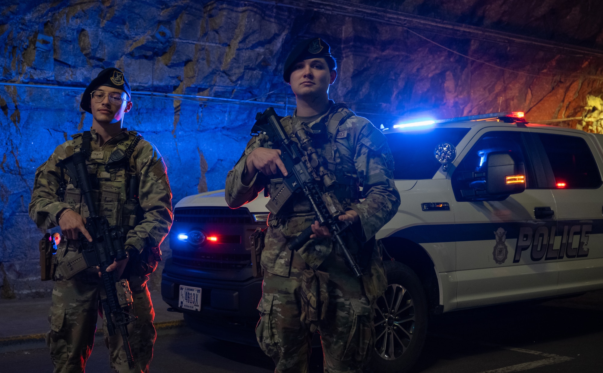 Both Aiman 1st Class Brock and Senior Airman Dustin Tietjen, pose in front of a patrol vehicle.