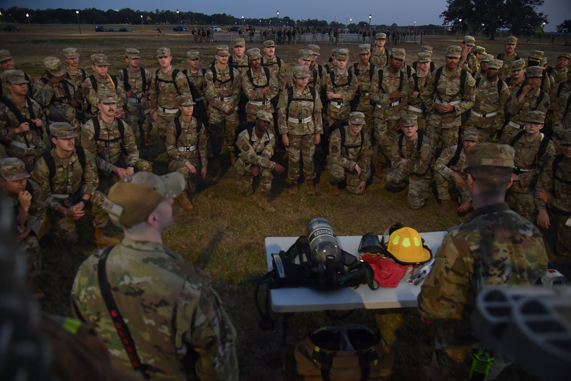 A firefighter speaks to a group of people in military uniform.