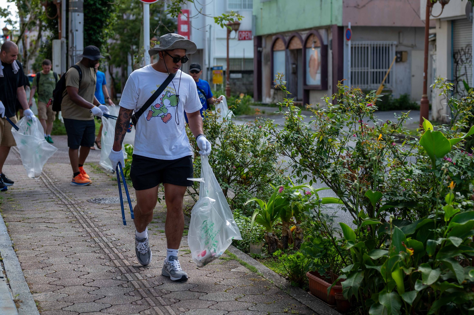 A U.S. Service member joins Okinawan volunteers to pick up trash during a bilateral community cleanup event at Kadena Air Base, Japan, Aug. 17 and 31, 2025.