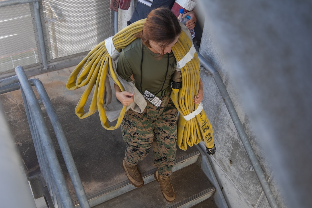 U.S. Marine Corps Cpl. Elise Pauss, a meteorological and oceanographic (METOC) Marine, with Headquarters and Headquarters Squadron (H&HS), Marine Corps Air Station Iwakuni, and a Mississippi native, carries a fire hose during the 12th annual 9/11 memorial stair climb at MCAS Iwakuni, Japan, Sept. 11, 2025. The 9/11 memorial stair climb's purpose is to honor those who lost their lives in the September 11, 2001, attack. Participants ascended a total of 110 floors to replicate the difficulties faced by New York City firefighters during rescue efforts. (U.S. Marine Corps photo by Sgt. Daniel Guerrero)