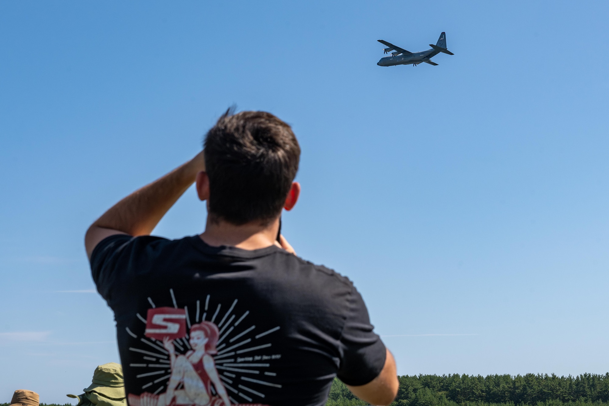 A participant takes photos of a U.S. Air Force C-130J Super Hercules doing a flyover during Range Day 2025 at Draughon Range.