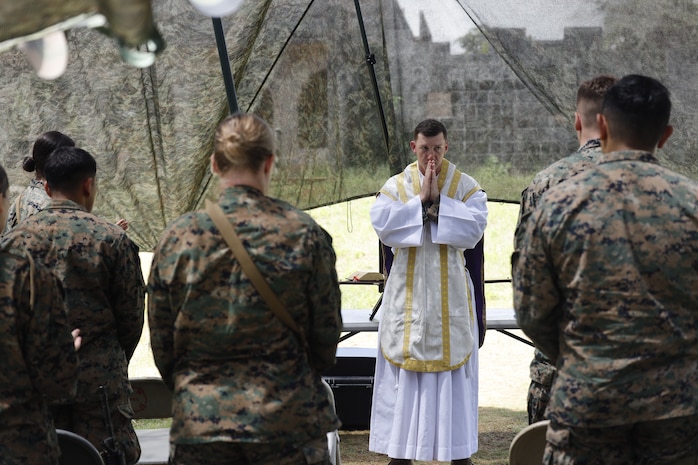 U.S. Navy Lt. Rene Pellessier, a Chaplain, administers Catholic Mass to Marine and Sailors with the III Marine Expeditionary Force outside the combat operations center in Combat Town, Camp Hansen, Okinawa Japan, Sept. 14, 2025, during the Command Post Exercise portion of Resolute Dragon 25. Resolute Dragon 25 is an annual bilateral exercise across Japan, including the southwest islands, that strengthens the command, control and multidomain maneuver capabilities of III MEF and the Japan Ground Self-Defense Force’s Western Army personnel, alongside representatives across the U.S. and Japanese Joint Force, with a focus on controlling and defending key maritime terrain. (U.S. Marine Corps photo by Gunnery Sgt. Daniel Wetzel)