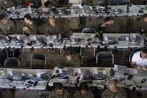 U.S. Marines and Sailors with III Marine Expeditionary Force conduct simulated battle drills while working in the III MEF combat operations center in Combat Town, Camp Hansen, Okinawa Japan, Sept. 13, 2025, during the Command Post Exercise portion of Resolute Dragon 25. Resolute Dragon 25 is an annual bilateral exercise across Japan, including the southwest islands, that strengthens the command, control and multidomain maneuver capabilities of III MEF and the Japan Ground Self-Defense Force’s Western Army personnel, alongside representatives across the U.S. and Japanese Joint Force, with a focus on controlling and defending key maritime terrain. (U.S. Marine Corps photo illustration by Gunnery Sgt. Daniel Wetzel) Photo has been edited for operational security.