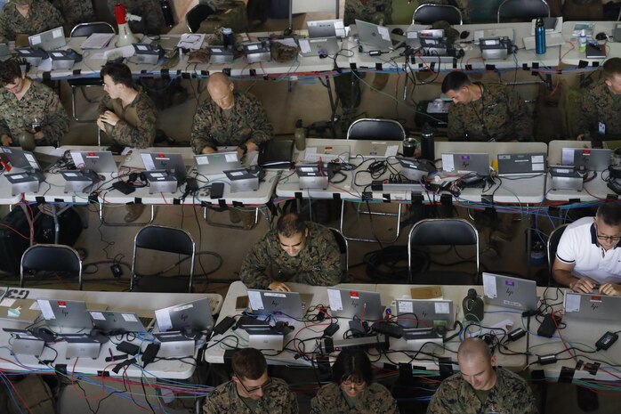 U.S. Marines and Sailors with III Marine Expeditionary Force conduct simulated battle drills while working in the III MEF combat operations center in Combat Town, Camp Hansen, Okinawa Japan, Sept. 13, 2025, during the Command Post Exercise portion of Resolute Dragon 25. Resolute Dragon 25 is an annual bilateral exercise across Japan, including the southwest islands, that strengthens the command, control and multidomain maneuver capabilities of III MEF and the Japan Ground Self-Defense Force’s Western Army personnel, alongside representatives across the U.S. and Japanese Joint Force, with a focus on controlling and defending key maritime terrain. (U.S. Marine Corps photo illustration by Gunnery Sgt. Daniel Wetzel) Photo has been edited for operational security.