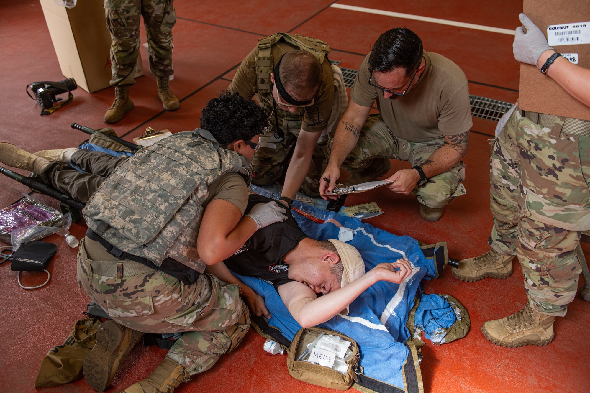 A group of Airmen practice tactical combat casualty care on a patient lying on a stretcher.