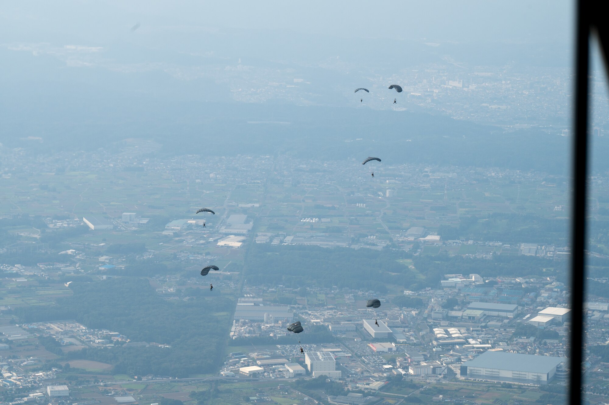 Service members jump out of an aircraft.