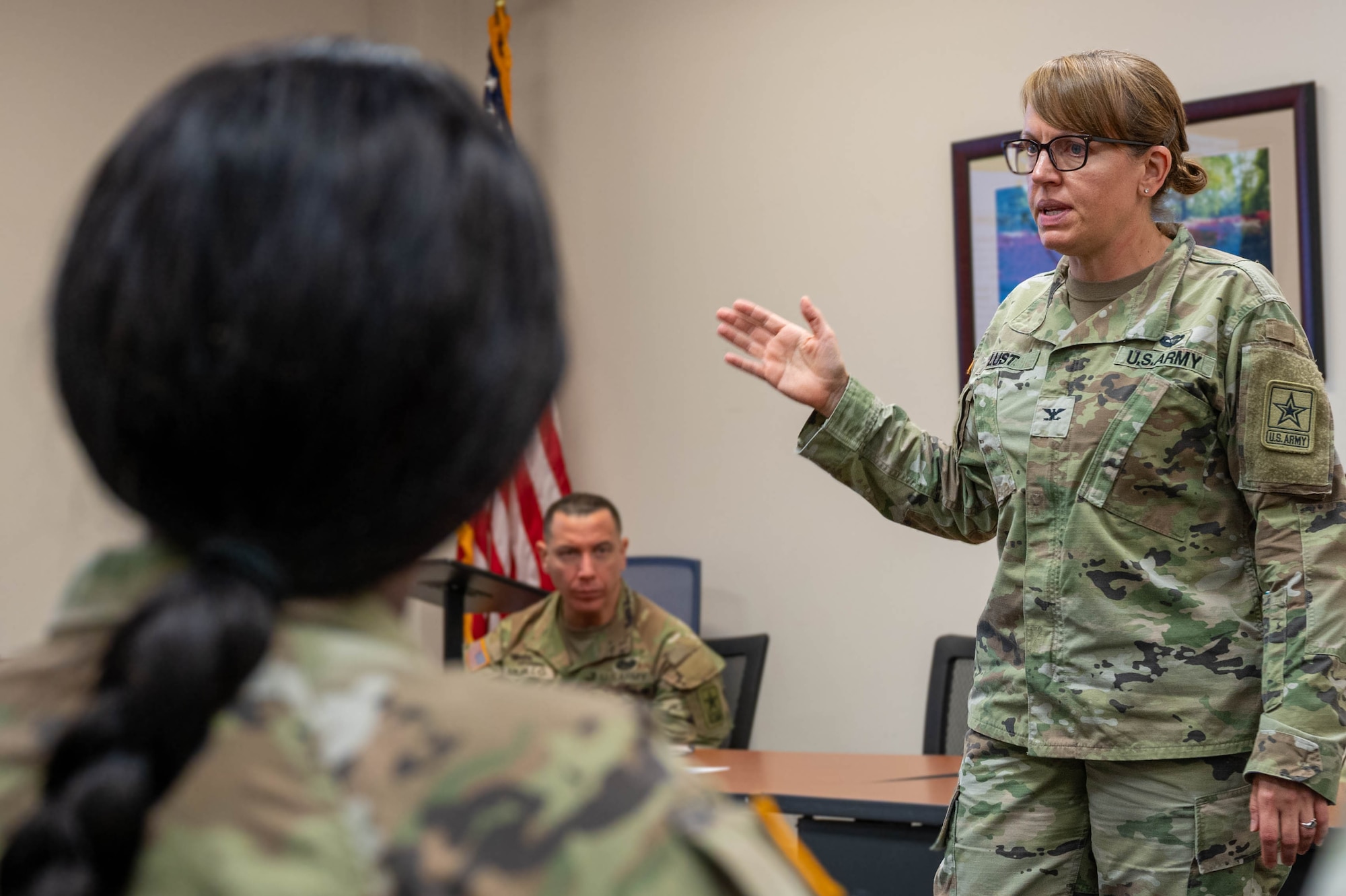 Women standing in front of a seated soldier giving a presentation.
