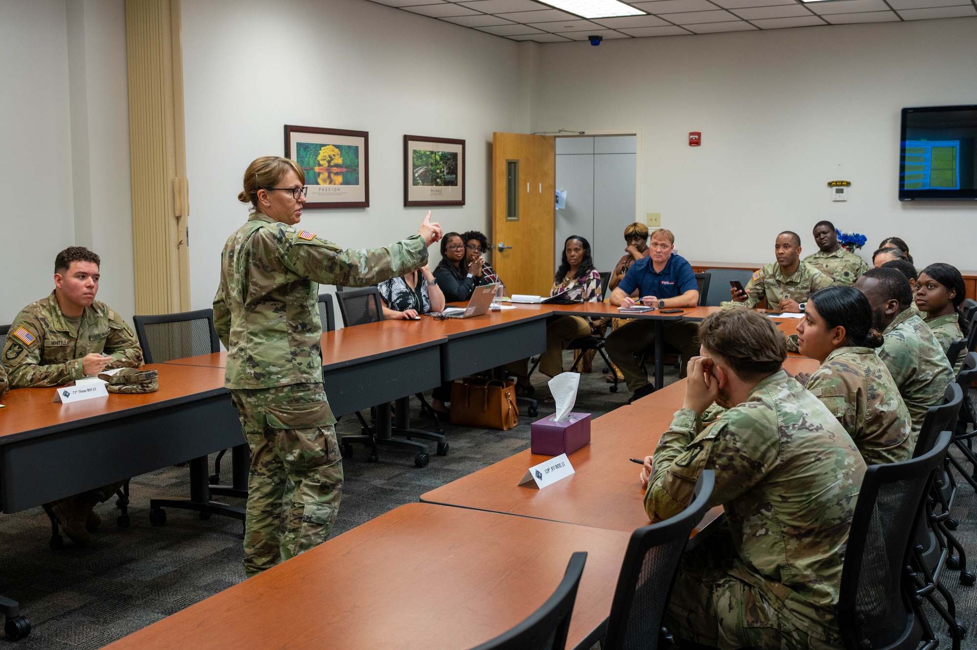 Women standing in front of a semi-circle of seated people, giving a presentation.