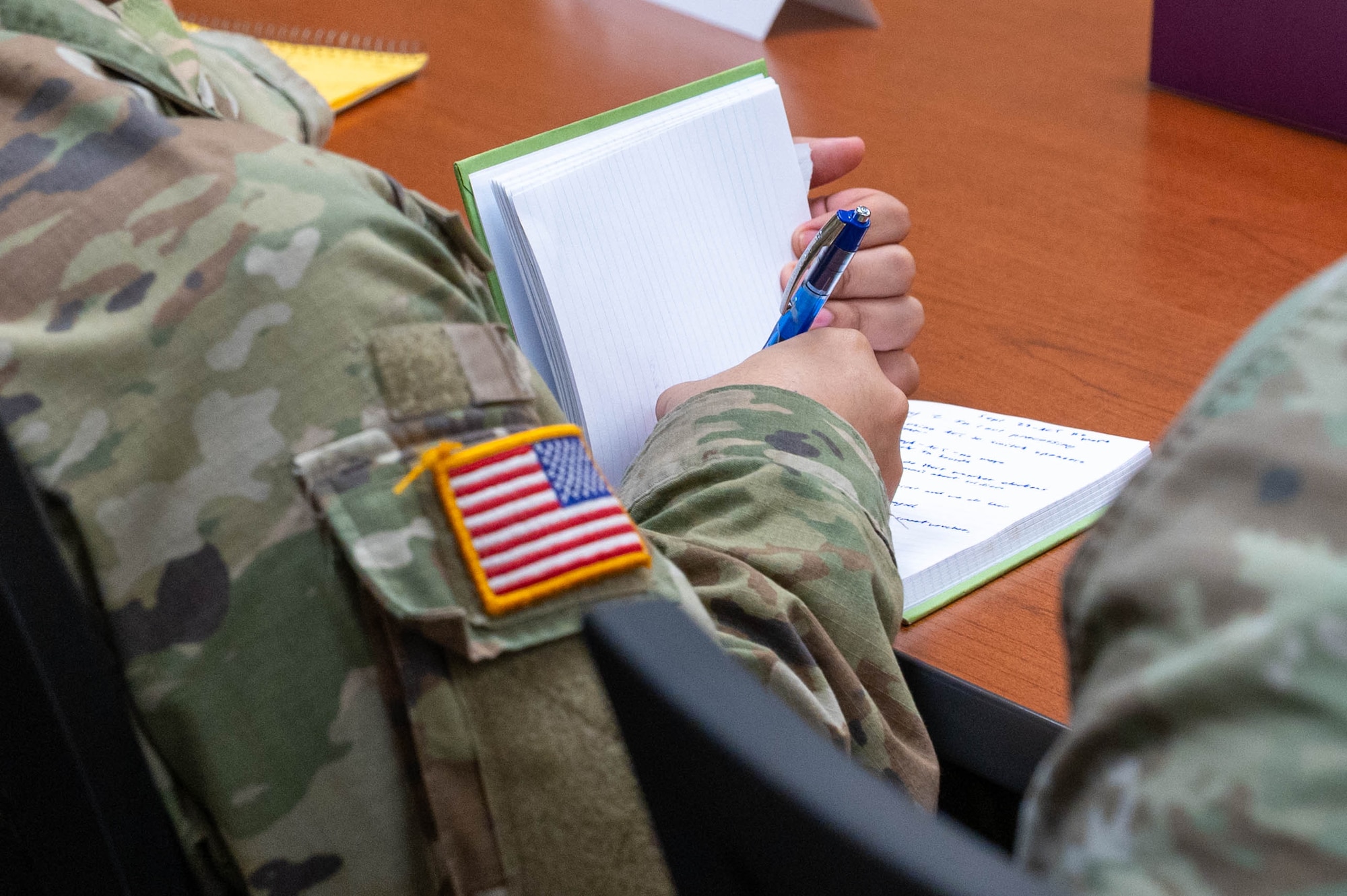 Solider using a pen to take notes in a notebook.