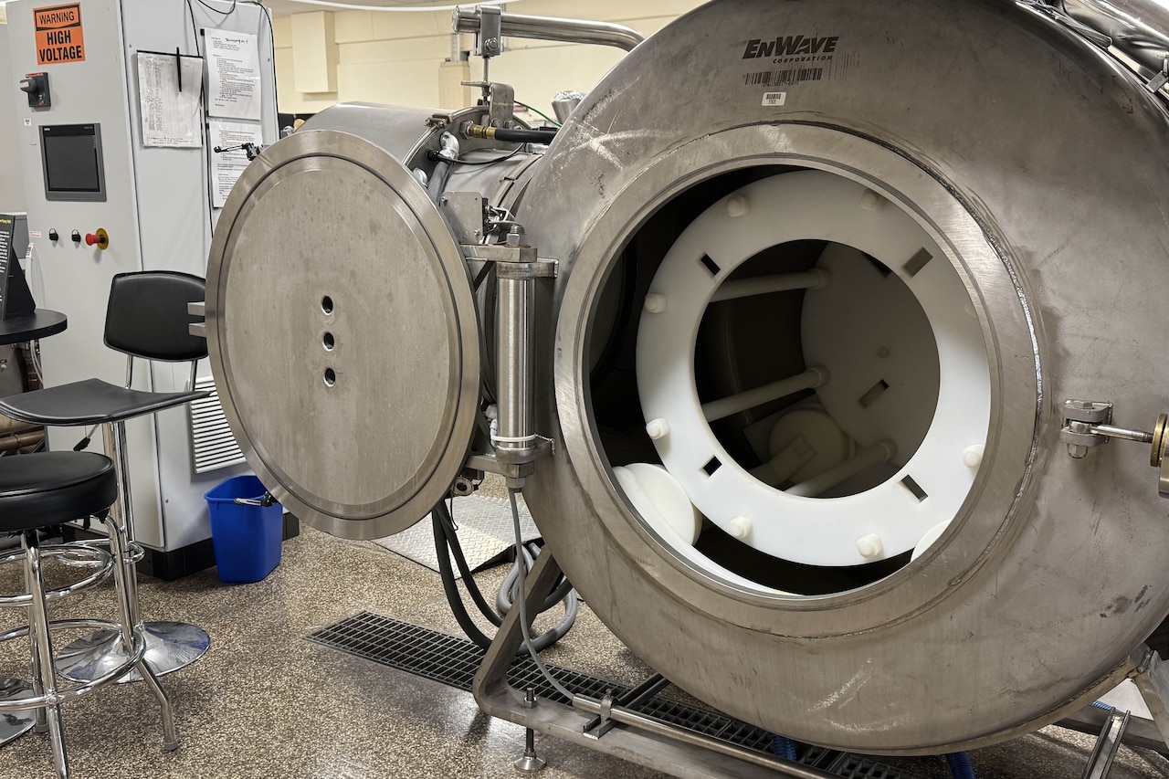 The door to a large, round metal machine sits open.