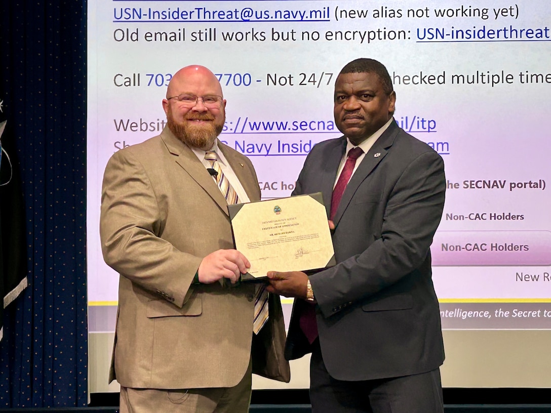 Two men pose while holding a certificate