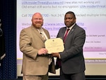 Two men pose while holding a certificate
